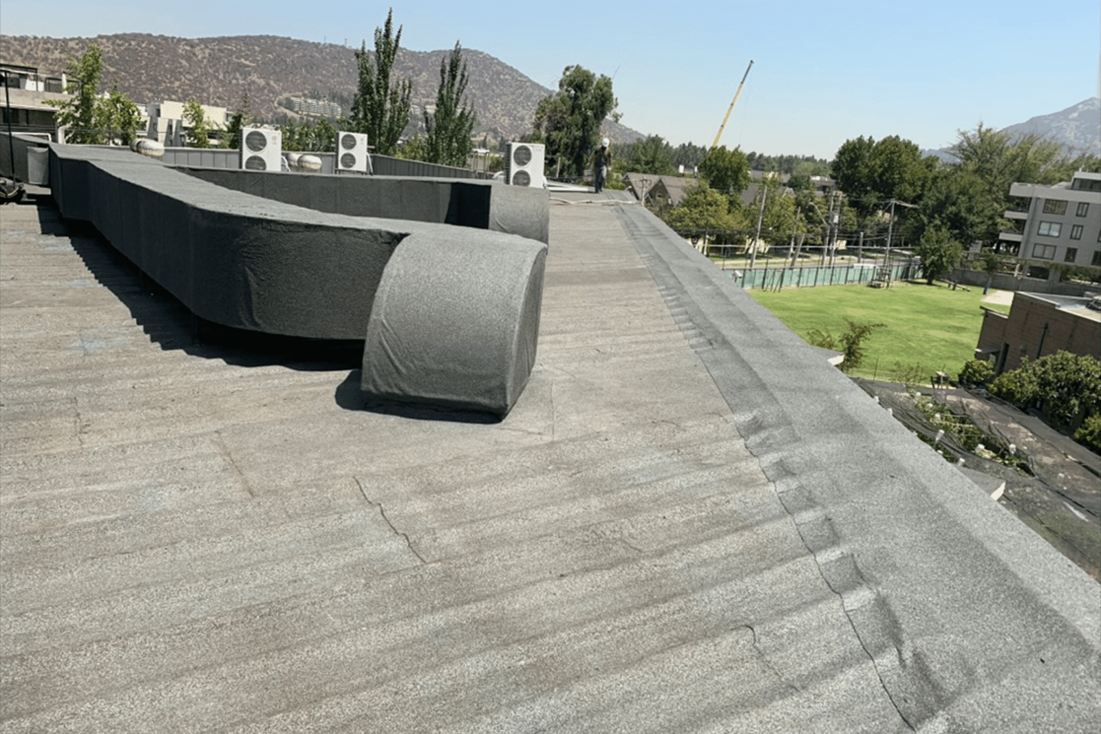 Azotea impermeabilizada con membrana asfáltica gris y ductos técnicos recubiertos.