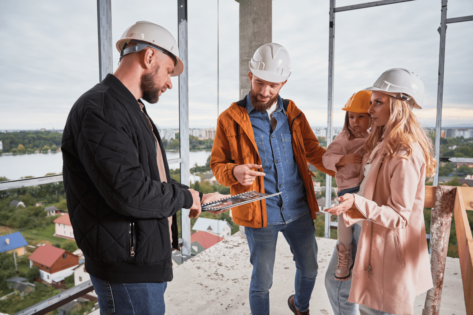 Ingeniero asesorando a clientes con familia en obra de construcción.