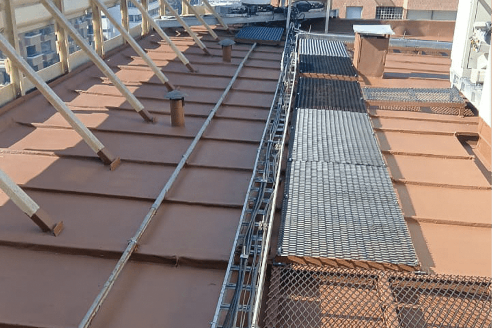 Renovación de cubierta metálica en edificio con instalación de rejillas de seguridad y refuerzos estructurales para trabajos de techumbre.